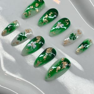 May include: Set of ten green and white false nails with gold leaf accents and shamrock designs.