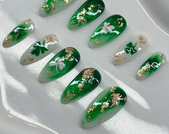 May include: Set of ten green and white false nails with gold leaf accents and shamrock designs.