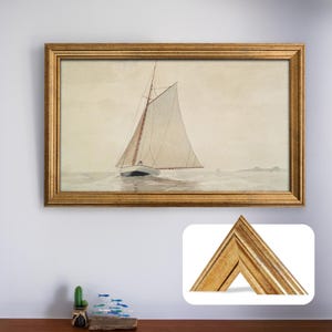 Puede incluir: Pintura en acuarela enmarcada de un velero sobre el agua. La obra de arte está en un marco dorado. El velero tiene una vela blanca sobre un fondo neutro. El marco es rectangular.