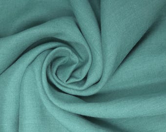 May include: A close-up of a soft, teal fabric with a smooth, even texture. The fabric is folded and draped, creating a flowing, organic shape.