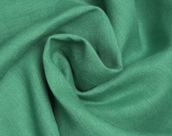 May include: A close-up of a soft, green fabric with a textured weave. The fabric is folded and draped, showing its texture and drape.