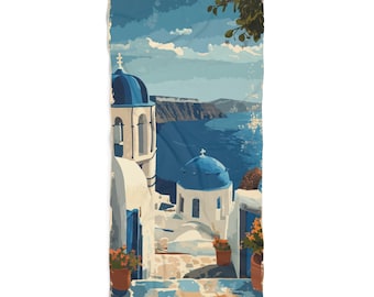 May include: A beach towel featuring a scenic illustration of a Greek island village. The artwork depicts white buildings with blue domes and accents, terracotta pots with flowers, and a view of the sea under a blue sky.