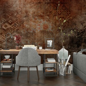 May include: A home office setup featuring a wooden desk with a black and white striped chair. The desk has a metal frame and shelves, with a lamp, books, and decorative items. The background is a textured brown wall.