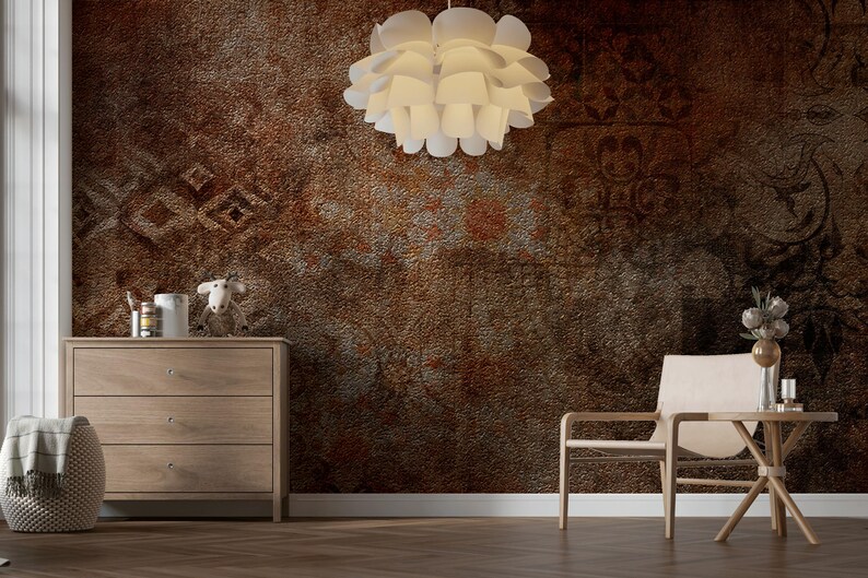 May include: A room with a textured, brown wall and a wooden floor. A white, layered pendant light hangs from the ceiling. Furnishings include a wooden dresser, a chair, and a small table. Decorative items are on the dresser and table.