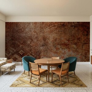 May include: A mid-century modern living room with a brown textured accent wall. The room features a round wooden table, four chairs, a sofa, and a patterned rug. Teal chairs and a wooden cabinet add color.