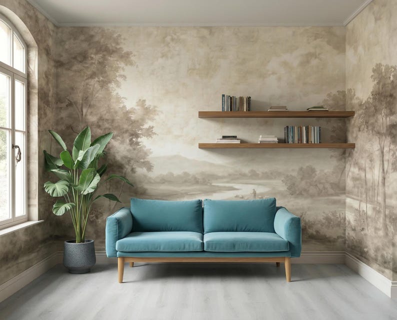 May include: A teal blue sofa with wooden legs sits in a room with a landscape mural. A large potted plant and two wooden shelves with books are also present. The room has a light gray floor and a window.