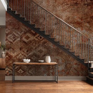 May include: A modern entryway with a staircase and a decorative console table. The staircase has dark metal railings and steps, with a textured, patterned wall in shades of brown. The console table holds a white vase and bowl.