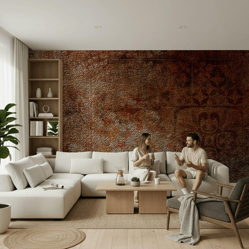 May include: A modern living room with a large, off-white sectional sofa, a light wood coffee table, and a textured, reddish-brown accent wall. A couple is seated on the sofa, and a wooden bookshelf is visible. The room has a neutral color palette.