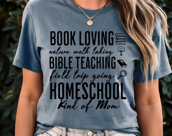 May include: A blue t-shirt with the text "Book Loving, Nature Walk Taking, Bible Teaching, Field Trip Going, Homeschool Kind of Mom" in black text. The text is surrounded by icons related to the text.