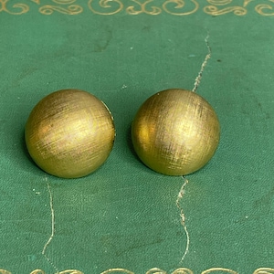 Peut inclure: Une paire de boucles d'oreilles rondes dorées avec une surface texturée.