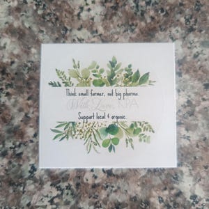 Puede incluir: Una pegatina cuadrada blanca con ilustraciones botánicas verdes y texto. El texto dice: "Think small farmer, not big pharma. With Love, KPA. Support local & organic."