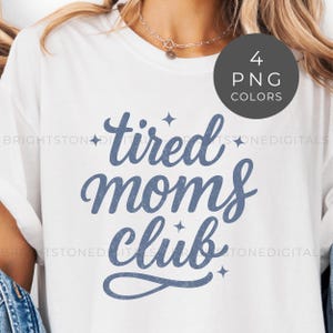 May include: White t-shirt with the text "tired moms club" in a blue script font. The design includes small star accents. A circular graphic in the upper right corner indicates 4 PNG color options.