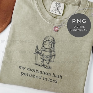 May include: A light green t-shirt featuring a cartoon frog in knight's armor holding a sword. The text "my motivation hath perished m'lord" is below the frog. A silver necklace with a pink pendant is also visible.