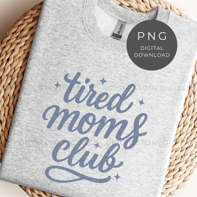 May include: Light gray sweatshirt with the text "tired moms club" in blue script. The sweatshirt has a crew neck and long sleeves. A digital download PNG graphic is in the upper right corner.