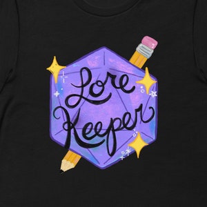 May include: Black t-shirt with a purple and blue illustrated dice with the text "Lore Keeper" and a yellow pencil.
