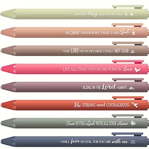 May include: A collection of eight pastel-coloured pens, each bearing a different inspirational quote in white lettering. The pens are in shades of green, peach, brown, pink, purple, orange, grey, and blue. Each pen has a different quote.