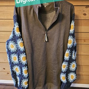 May include: A gray quarter-zip sweatshirt with crochet daisy sleeves. The sleeves are made of dark blue squares with yellow and light blue daisy designs. The text "Digital Pattern Only" is displayed on a green banner.