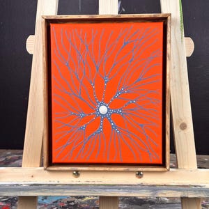 May include: A framed canvas painting with a bright orange background and a blue and white abstract design resembling a tree with branches.