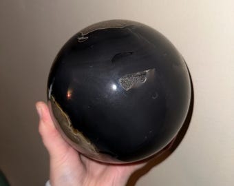 Peut inclure: Une sphère noire polie avec une petite section brun clair. La sphère est en pierre naturelle et a une finition lisse et brillante.