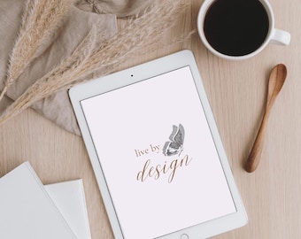 May include: A white tablet computer with a gray butterfly graphic and the text "live by design" in brown lettering.