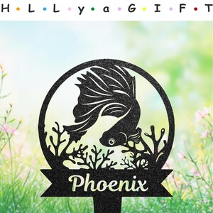 Peut inclure: Piquet de jardin en métal noir avec une silhouette de poisson combattant dans un cercle avec du corail et le mot "Phoenix" sur une bannière.