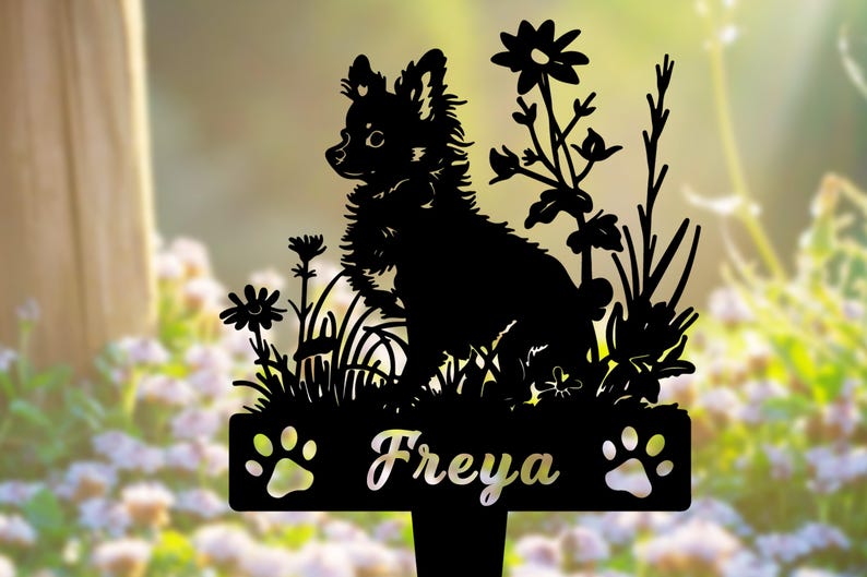 K&ouml;nnte beinhalten: Schwarze Metallsilhouette eines kleinen Hundes, der in einem Blumenfeld sitzt, mit dem Namen "Freya" auf einer darunter liegenden Plakette.