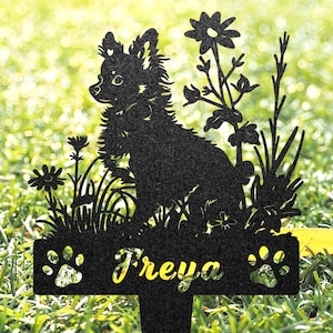 K&ouml;nnte beinhalten: Schwarze Metallsilhouette eines Chihuahua-Hundes mit Blumen und dem Namen "Freya" auf einer Plakette. Die Silhouette befindet sich auf einem gr&uuml;nen Gras Hintergrund.