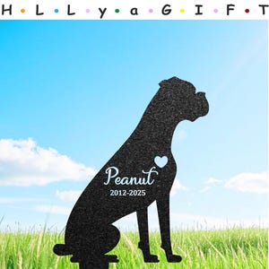 Puede incluir: Silueta negra de metal de un boxer sentado con un corazón y el nombre "Peanut" y las fechas "2012-2025" sobre un fondo de hierba verde.