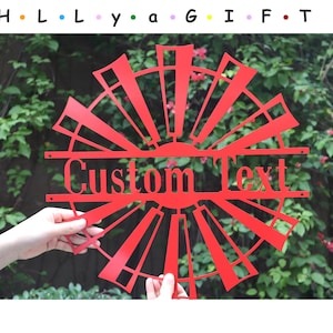Può includere: Design a forma di mulino a vento in metallo rosso con uno stendardo di testo personalizzato. Lo stendardo dice "Custom Text".