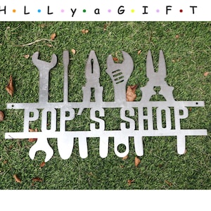 May include: Metal sign with the words "Pop's Shop" and a row of various tools, including a wrench, screwdriver, pliers, and a hammer.