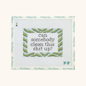 May include: A white needlepoint canvas featuring a central rectangular border with a green and blue chevron pattern. The text "can somebody clean this shit up?" is printed in black in the center. The brand name "Pin & Pattern" is on the edges.