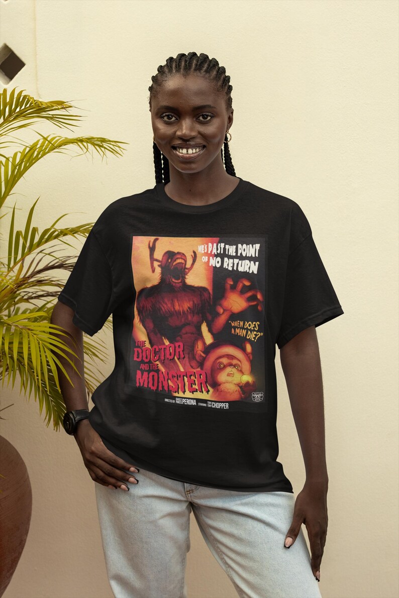 May include: Black t-shirt featuring a vintage-style movie poster with the text "THE DOCTOR AND THE MONSTER." The poster includes the phrases "HES PAST THE POINT OF NO RETURN" and "WHEN DOES A MAN DIE?" The design is in shades of red, orange, and brown.