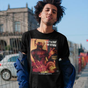 May include: Black t-shirt featuring a vintage movie poster design. The poster art depicts a monster with the text "THE DOCTOR AND THE MONSTER" and "PAST THE POINT OF NO RETURN". The shirt has a classic crew neck.