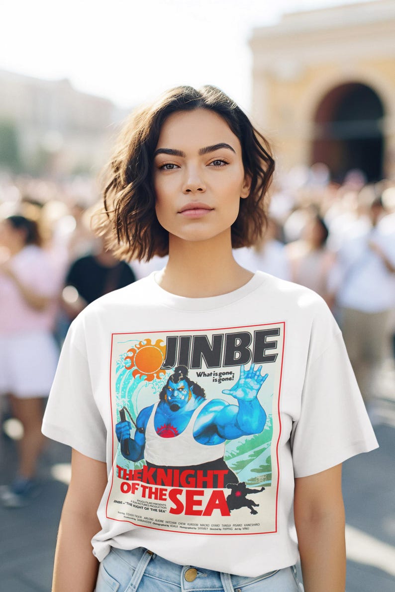 May include: White t-shirt featuring a colorful graphic of a blue character with the text "JINBE" and "THE KNIGHT OF THE SEA". The design includes a sun, waves, and the phrase "What is gone, is gone!"