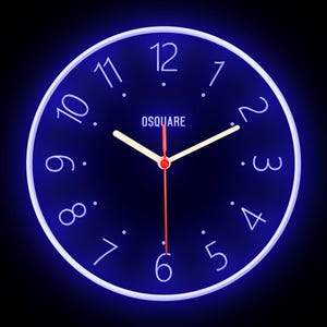 Op de afbeelding: Een ronde, blauwe klok met witte cijfers en een witte rand. De wijzerplaat van de klok is zwart met witte uur- en minutenwijzers en een rode secondewijzer. Op de wijzerplaat van de klok staat ook het woord "OSQUARE".