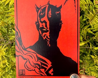 Op de afbeelding: Een rechthoekige kunstdruk met een contrastrijk zwart silhouet van een gehoornd personage met gele ogen tegen een felrode achtergrond. Het ontwerp bevat gestileerde zwarte rook, een zon-element en rode tekst aan de onderzijde.