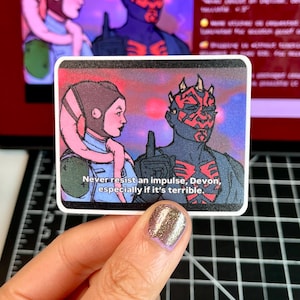 May include: A square sticker with a comic-style illustration of two characters. One is a dark-skinned male with red markings and horns, the other a light-skinned female with pink appendages. The text reads, "Never resist an impulse, Devon, especially if it's terrible."