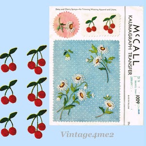 Peut inclure: Feuille de transfert Kaumagraph McCall's vintage avec des motifs de marguerites et de cerises pour la garniture de vêtements et de linge. La feuille comprend des motifs brodés de cerises et de marguerites en rouge, vert et blanc. Le texte "Vintage4me2" est visible.