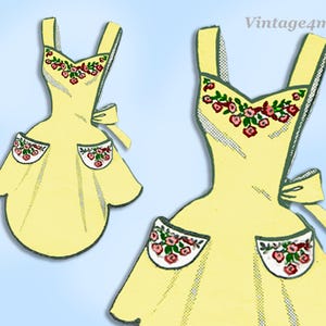 Könnte beinhalten: Eine gelbe Schürze mit floralem Design. Die Schürze hat einen V-Ausschnitt, Träger und zwei Taschen. Die Taschen und der Halsausschnitt sind mit roten und rosa Rosen verziert. Hinten ist eine Schleife gebunden. Der Text "Vintage4me2" steht oben rechts.