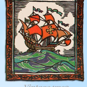 May include: A framed vintage print of a sailing ship on a wavy sea. The ship has orange sails and green and purple waves. The frame is dark with an orange border. The text "Vintage4me2" is at the bottom.