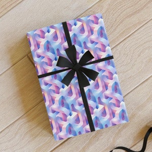 May include: A gift wrapped in blue and pink geometric patterned paper with a black ribbon and bow. The gift is on a wooden surface with black ribbon, a spool of ribbon, pencils, and a pair of scissors.