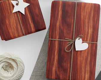 Peut inclure: Trois boîtes cadeaux en bois enveloppées de ficelle brune et décorées d'étoiles et de cœurs en papier blanc. Les boîtes sont sur une surface en tissu gris avec une bobine de ficelle et une paire de ciseaux.