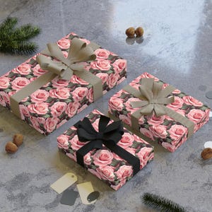 May include: Three gift boxes wrapped in pink floral patterned paper with brown, beige, and black ribbon bows. The boxes are on a gray textured surface.