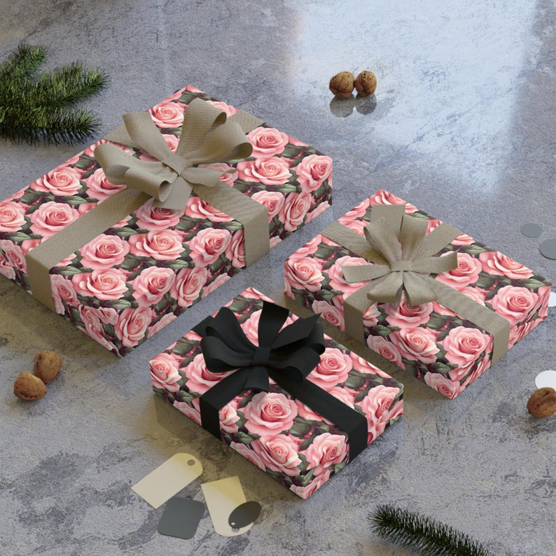 May include: Three gift boxes wrapped in pink floral patterned paper with brown, beige, and black ribbon bows. The boxes are on a gray textured surface.