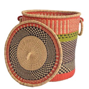 May include: A woven storage basket with a lid. The basket is cylindrical with a red, orange, green, and black pattern. The lid is round with a spiral design in tan, black, and red. The basket has two handles.
