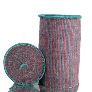 May include: A tall, cylindrical woven basket with a matching lid. The basket and lid are teal and red striped. The lid is round and sits next to the basket. The basket has a teal rim.
