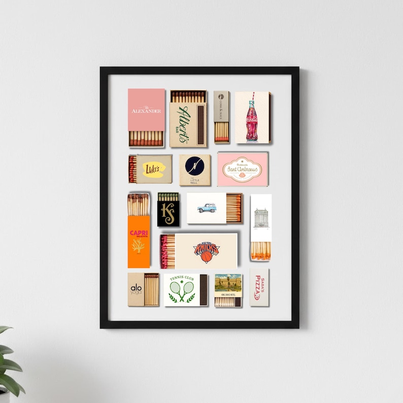 May include: A framed print featuring a collection of vintage matchboxes. The matchboxes are in various colors and designs, with text and graphics. The brands include "Alexander", "Albert's", "Lukes", "Capri", "Alo Yoga", and "Pizza".