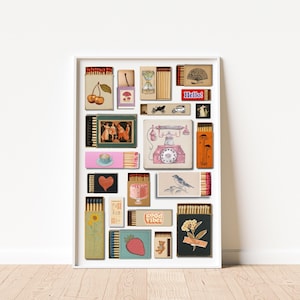 May include: A framed art print showcasing a collage of vintage matchboxes, each with unique illustrations. The artwork includes images of cherries, a teacup, a telephone, a bird, and the text "Hello!" and "good vibes". The color scheme is soft and vintage.