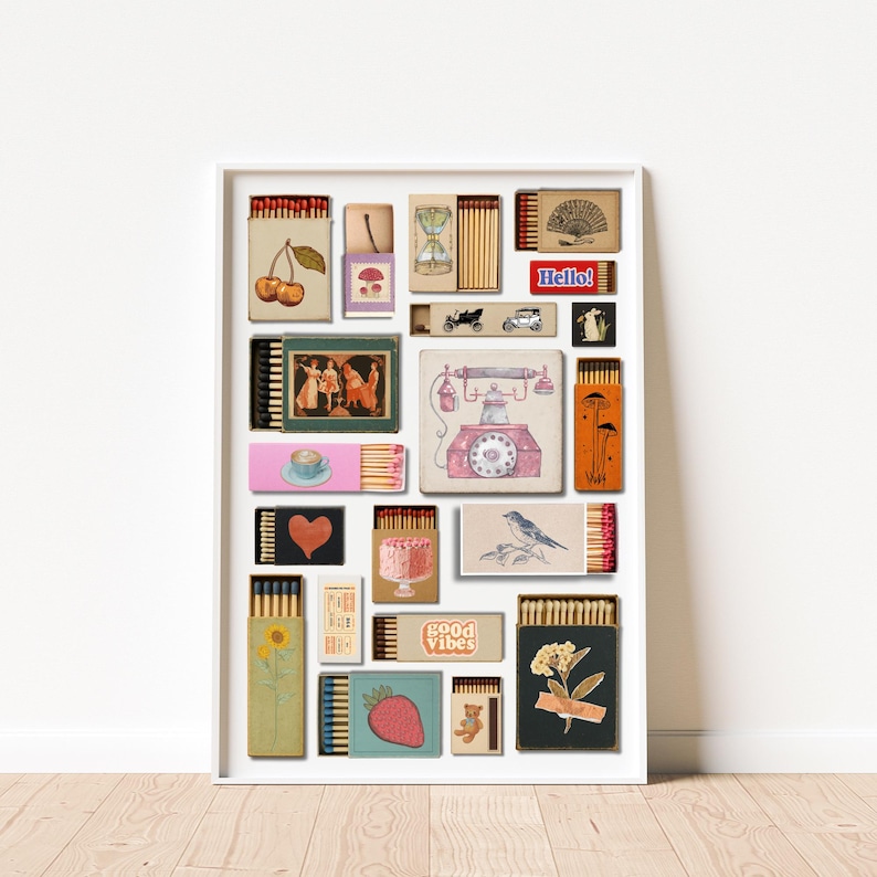 May include: A framed art print showcasing a collage of vintage matchboxes, each with unique illustrations. The artwork includes images of cherries, a teacup, a telephone, a bird, and the text "Hello!" and "good vibes". The color scheme is soft and vintage.