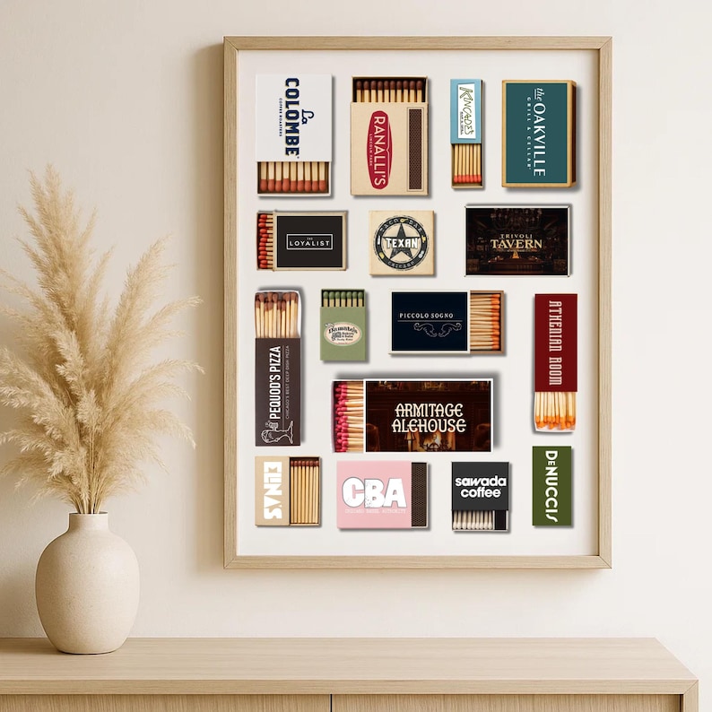 May include: A framed print featuring various matchbox designs. The matchboxes display text such as "COLOMBE", "RANALLI'S", "the OAKVILLE", "LOYALIST", "TEXAN", "TAVERN", "PICCOLO SOGNO", "PEQUOD'S PIZZA", "ATHENIAN ROOM", "DENUCCIS", "ARMITAGE ALEHOUSE", "CBA", and "sawada coffee".